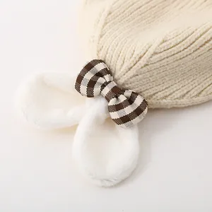 Détail du bonnet tricoté pour bébé avec oreilles de lapin et nœud en tissu à carreaux