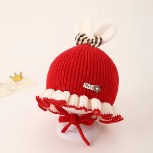 Détail du bonnet tricoté rouge pour bébé avec oreilles de lapin en peluche et nœud rayé