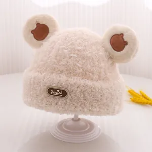 Dettaglio del berretto in maglia con pompon a orecchie di orso ed etichetta in pelle