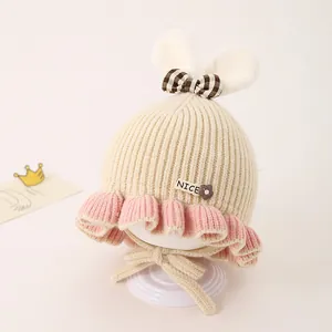 Détail de la maille du bonnet d'hiver bébé avec oreilles en peluche et nœud décoratif