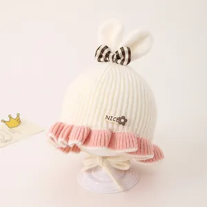 Détail du bonnet en tricot bébé avec oreilles de lapin, nœud rose et patch NICE