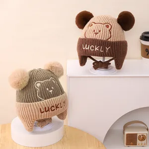 Warm winter knit hat for kids with bear embroidery, pom-poms, and protective ear flaps
