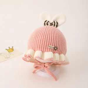 Détail d'un bonnet en tricot rose pour bébé avec oreilles de lapin et nœud à carreaux