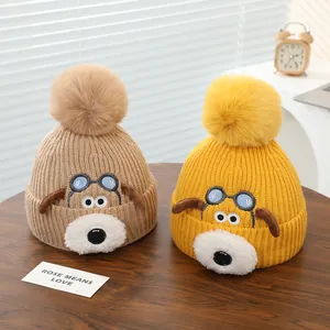 Gebreide babymutsen met schattig hondenborduurwerk en pluizige pompons in beige en geel