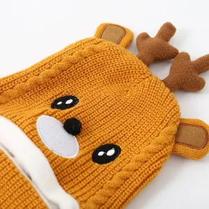 Detail der gelben Strickmütze mit Zopfmuster und 3D-Rentiergeweih für Kinder im Winter