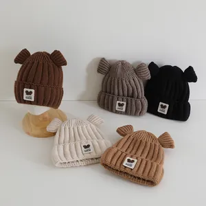 Détail de bonnets tricotés pour enfants avec oreilles d'ours en marron, gris, noir et crème