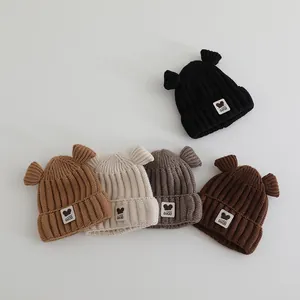 Detail van vijf babygebreide mutsen met berenoren en Fashion GOOD geweven label