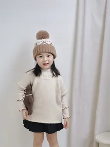Detail of children's warm knit hat with plush pom pom and matching scarf set
