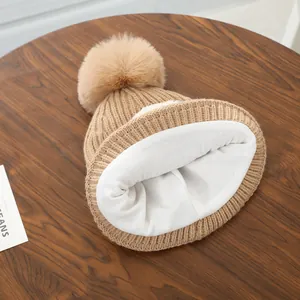 Detail van warme gebreide babymuts met dikke fleecevoering en grote pompon van imitatiebont