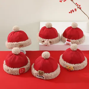 Detalle de gorros de peluche rojos para niños con bordados festivos y pompones blancos suaves