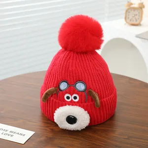 Detailopname van de rode gebreide kindermuts met schattig puppy-ontwerp en zachte pompon