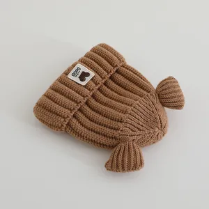 Détail de la maille d'un bonnet d'hiver marron pour bébé avec nageoires et logo tendance
