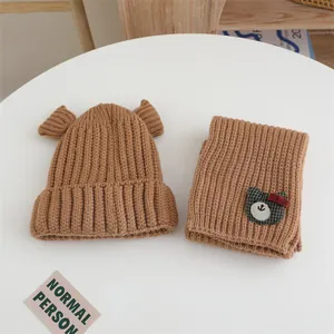 Détail de l'ensemble bonnet et écharpe en tricot marron avec écusson ours mignon