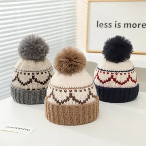 Detailed close-up of winter knit hats with pom-poms showing patterns and ribbing