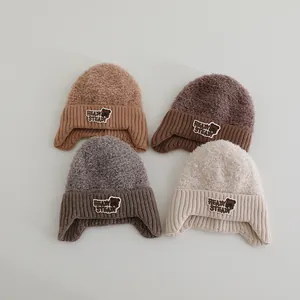 Detail von warmen Winterstrickmützen für Kinder in vier Farben mit Bären-Aufnäher