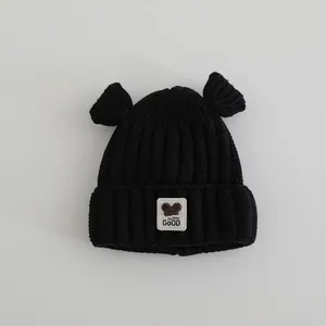 Détail d'un bonnet tricoté noir pour bébé avec oreilles rondes et écusson d'ourson