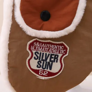 Macro view of brown fabric with embroidery badge and soft white faux fur trim detail
