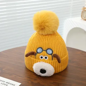Detail van gele gebreide babymuts met cartoon puppy met 3D-oren en een pompon van imitatiebont