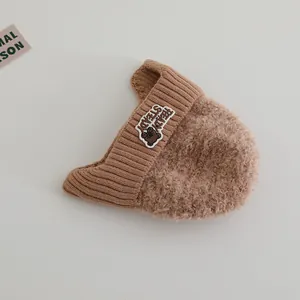 Detailansicht der Bären-Stickerei und Lammfell-Textur auf der Winter-Strickmütze