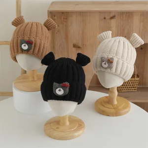 Détail de bonnets tricotés chauds pour bébé avec oreilles d'ours et écussons brodés