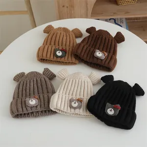 Détail de cinq bonnets en maille épaisse pour bébé avec oreilles d'ours et patchs décoratifs