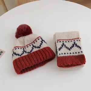 Detailed knit texture of children winter set with hat, scarf and pom-pom in cream and burgundy
