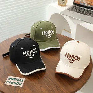 Three kids baseball hats with Hello smiley embroidery on a wooden table setup