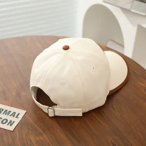 Detail of two-tone beige kids baseball cap with adjustable silver metal buckle on wood table