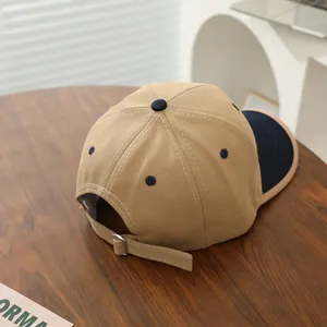 Detail of adjustable metal buckle and stitching on khaki and navy cotton baseball cap