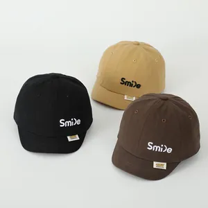Detailed close-up of cotton baby baseball caps with Smile embroidery in three neutral colors
