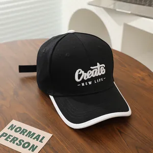 Detailopname van zwarte baseballpet met wit Create borduursel en wit omzoomde rand
