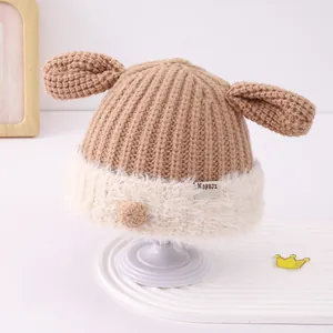 Detailed view of baby knit hat with brown ribbed texture and soft white faux fur trim