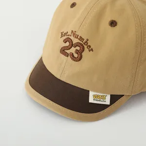 Detailed view of kids' khaki baseball cap with 23 embroidery and soft brim texture