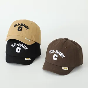 Close-up of cotton baby baseball caps in khaki, black and brown with 3D letter embroidery
