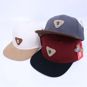 Détail de trois casquettes snapback en coton avec écussons C en cuir de couleurs