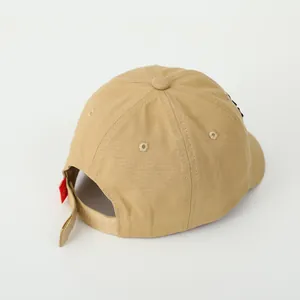 Detail view of khaki cotton baseball cap with adjustable strap and red brand tag