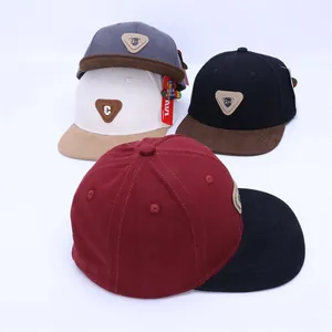 Gros plan de quatre casquettes hip-hop bicolores avec patchs logo en cuir