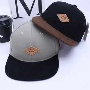 Detail view of cotton snapback hats with leather mountain patches and flat brims