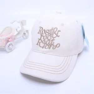 Detail of off-white baseball cap featuring brown embroidered letters and a curved brim