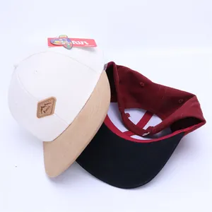 Detail view of cotton baseball caps showing flat brim, KUKUJI leather patch and buckle back