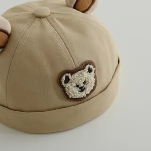 Close-up of khaki cotton toddler hat featuring teddy bear embroidery and plush ears