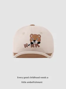 Dettaglio del cappellino da neonato in cotone beige con ricamo di orsetto
