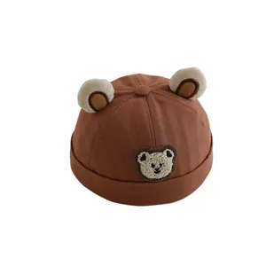 Brown canvas kids miki hat with plush bear ears and cartoon patch on white background