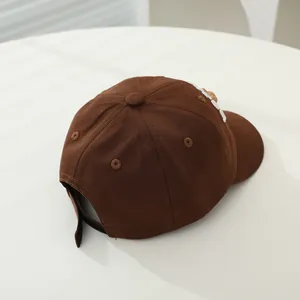 Detail of a brown cotton baseball cap showing 3D embroidery and adjustable strap