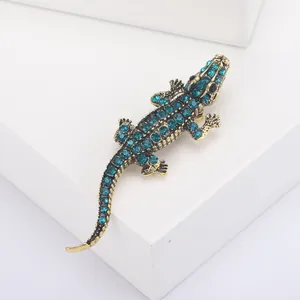 Detail shot of vintage gold crocodile brooch with sparkling blue rhinestones on white cubes