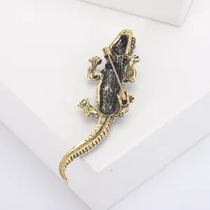 Macro view of the back of a gold crocodile brooch showing the pin clasp and scale texture