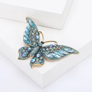 Detail van vintage vlinderbroche met blauwe kristallen op een wit blokje