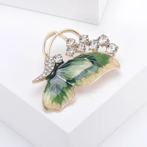 Close-up of alloy butterfly brooch with green enamel wings and sparkling rhinestones