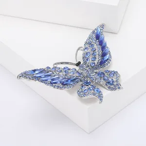 Gedetailleerde close-up van een zilverkleurige vlinderbroche met blauwe strassteentjes