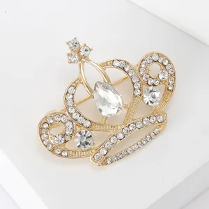 Détail d'une broche couronne en cristal doré avec une pierre en forme de goutte